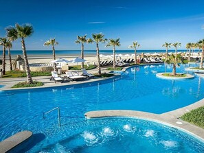 Ein Resortpool mit Liegestühlen und Palmen, umgeben von blauem Himmel.