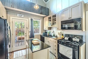 A modern kitchen with a central island, built-in appliances, and a view of the outdoors. - 10 min Walk to Downtown • Vintage Bungalow • Patio (McKinney)
