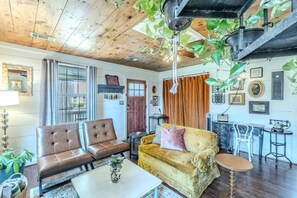 Un salon chaleureux avec un plafond en bois, un canapé, une table basse et un coin repas comprenant une table et des chaises.