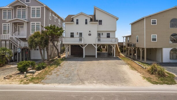 A multi-story residential building with a covered driveway and a front porch. - Beach Please, Ocean Front Retreat (Ocean Isle Beach)