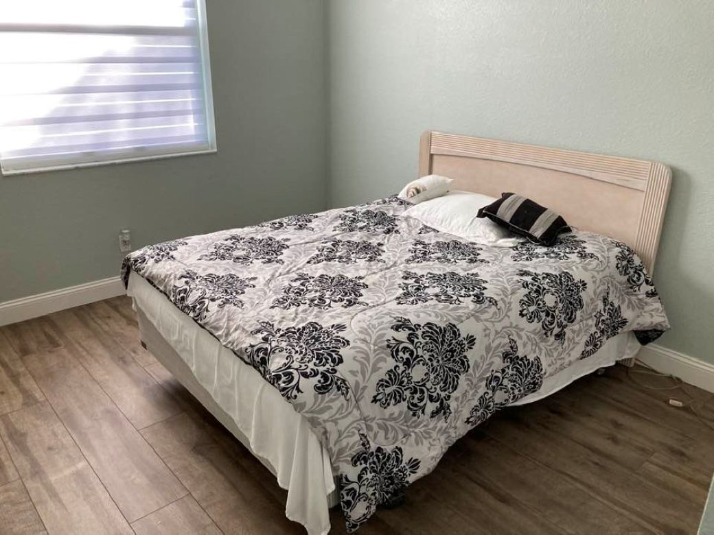 A bedroom with a bed, a window, and a wall.