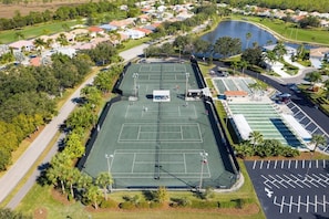 Vue aérienne d’un quartier résidentiel avec un court de tennis, un parking et une étendue d’eau.