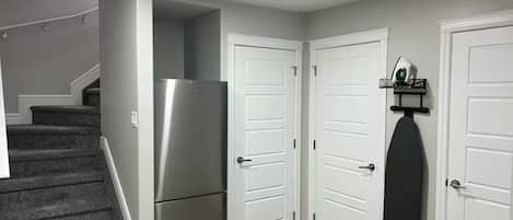 A hallway with a refrigerator, double doors, and a staircase.