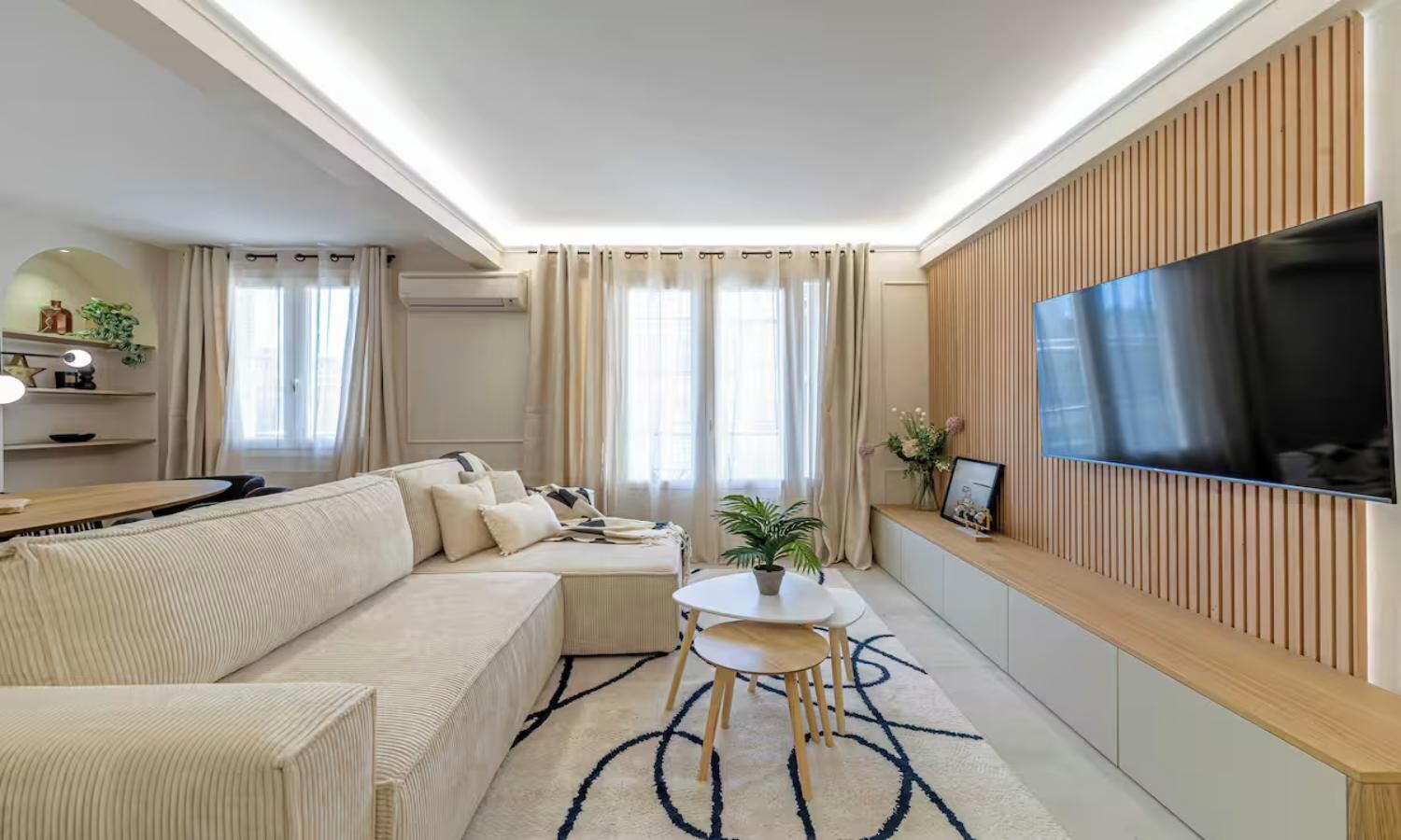 A modern living room with a sofa, a coffee table, and a flat-screen TV mounted on the wall.