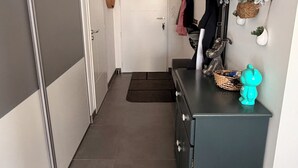 Ein Flur mit einem grauen Wandschrank, einem dunkelblauen Schrank und einer an der Wand befestigten Pflanzenanordnung.