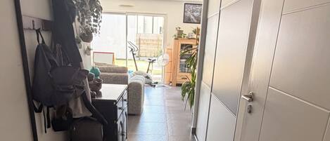 A narrow hallway with a bench, a coat rack, and a sliding door.