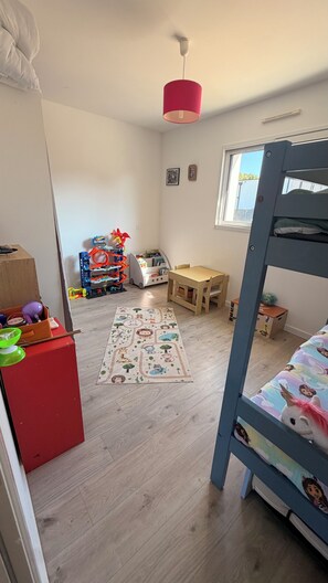 A child's room with a bunk bed, a wooden table, a colorful rug, and a toy storage unit. - Single-story house in Questembert, near Roche Fort en Terre, 25 minutes from the beaches (Questembert)