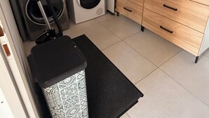 Ein kleiner Waschraum mit Waschmaschine, Trockner und übereinander gestapelten Wäschekörben.