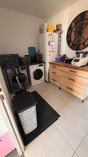 A compact laundry room with a washing machine, dryer, and stacked laundry baskets. - Single-story house in Questembert, near Roche Fort en Terre, 25 minutes from the beaches (Questembert)