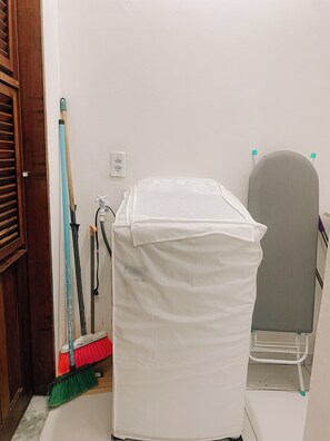 A room with a white covered object, a broom, and a chair. - A cozy, spacious home for families and couples (sleeps 6), just 5 minutes from the beach (Lagoinha Paraipaba)
