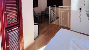 A bedroom with a bed, a wooden door, a staircase, and a seating area with chairs. - A cozy, spacious home for families and couples (sleeps 6), just 5 minutes from the beach (Lagoinha Paraipaba)