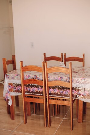 A dining table with a floral tablecloth and wooden chairs. - A cozy, spacious home for families and couples (sleeps 6), just 5 minutes from the beach (Lagoinha Paraipaba)