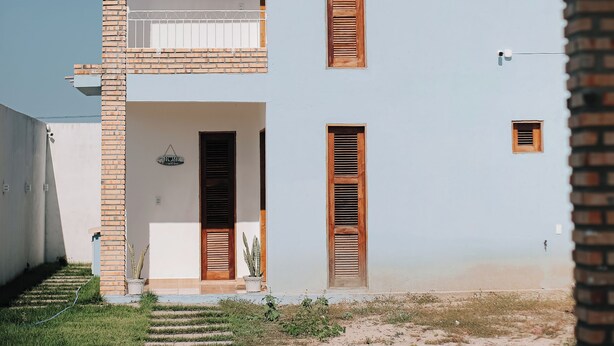 A two-story building with a balcony, a door, and a small window. - A cozy, spacious home for families and couples (sleeps 6), just 5 minutes from the beach (Lagoinha Paraipaba)