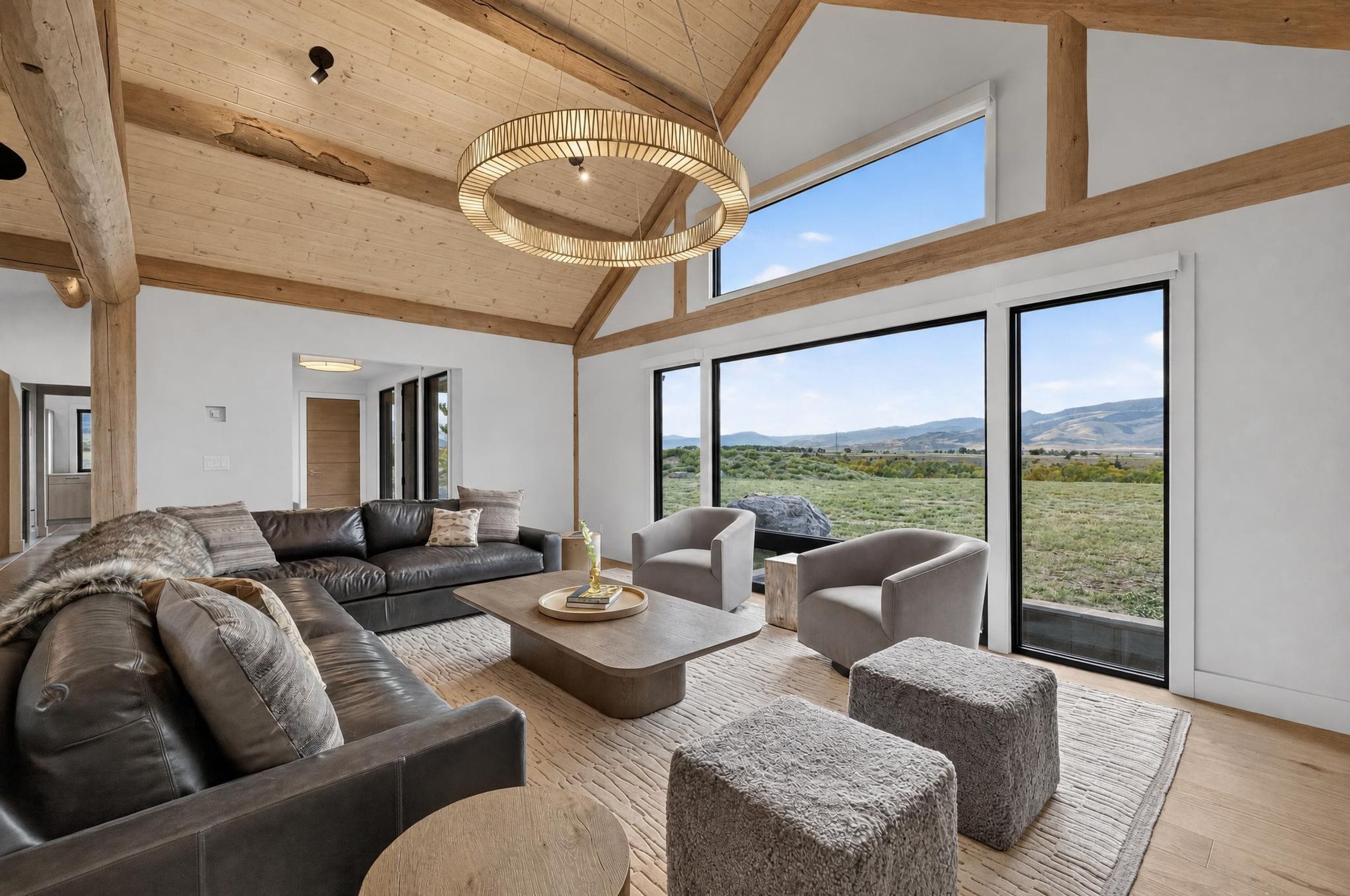 Un salon spacieux avec un grand canapé d’angle, une table basse et une vue sur l’extérieur grâce à de grandes fenêtres.