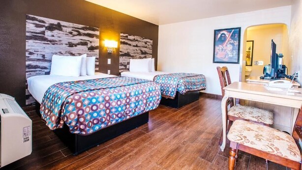 A hotel room with two beds, a desk, and a chair. - Deluxe Room with Two Queen Beds (Anaheim)