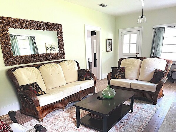 A living room with two sofas, a coffee table, and a mirror with a decorative frame.