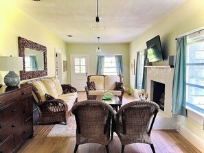 A living room with a fireplace, a sofa, a coffee table, and a television mounted on the wall.