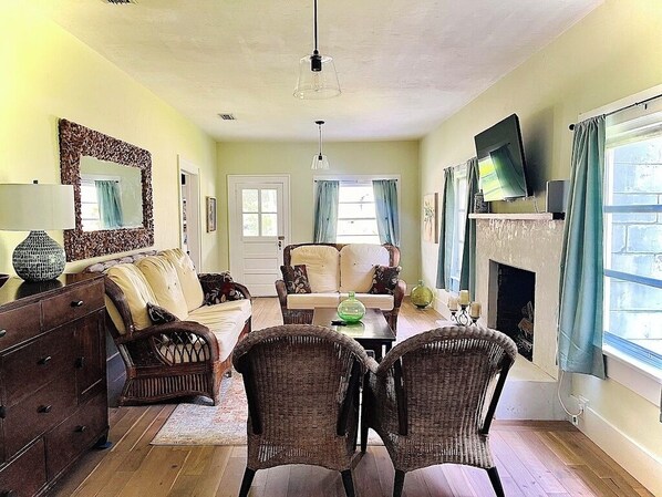 A living room with a fireplace, a sofa, a coffee table, and a television mounted on the wall.