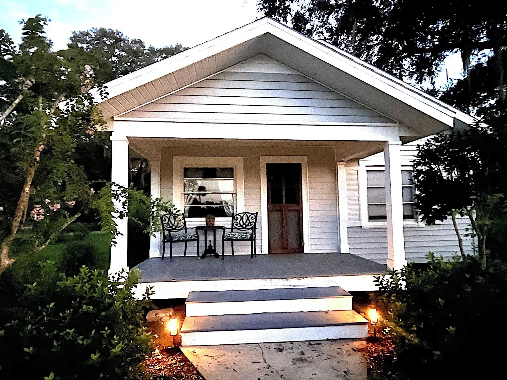 A two-story house with a front porch, a door, and a window.