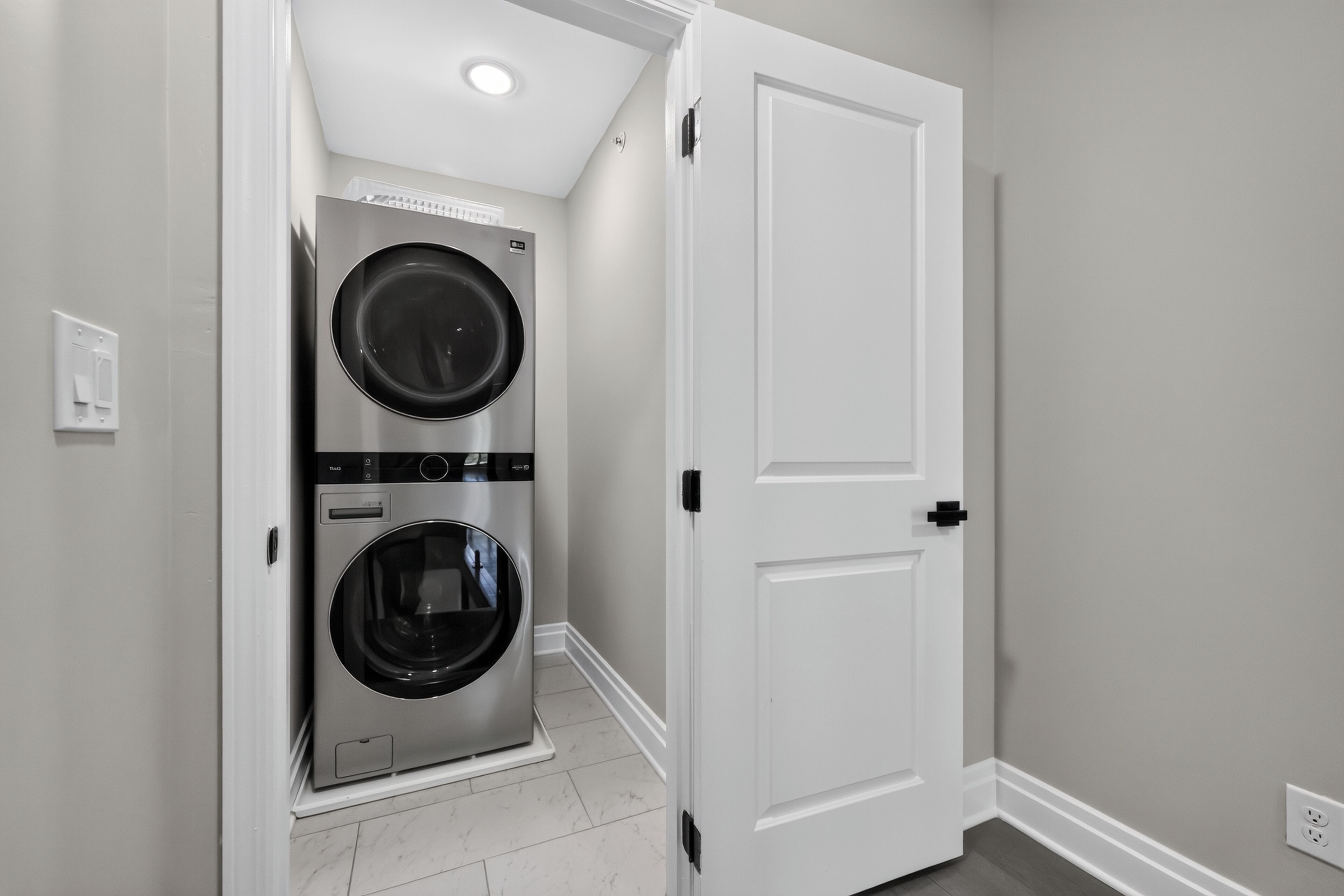A laundry room with two stacked front-loading washing machines and a white door.
