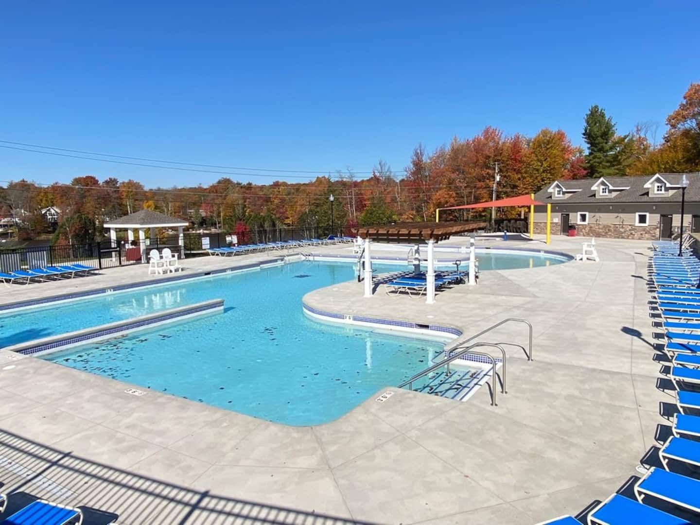 Une piscine avec plusieurs couloirs de nage, un espace de repos couvert et des chaises longues.