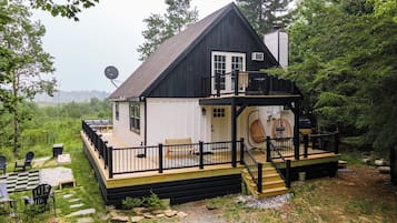A cabin with a deck, a small porch, and a satellite dish.