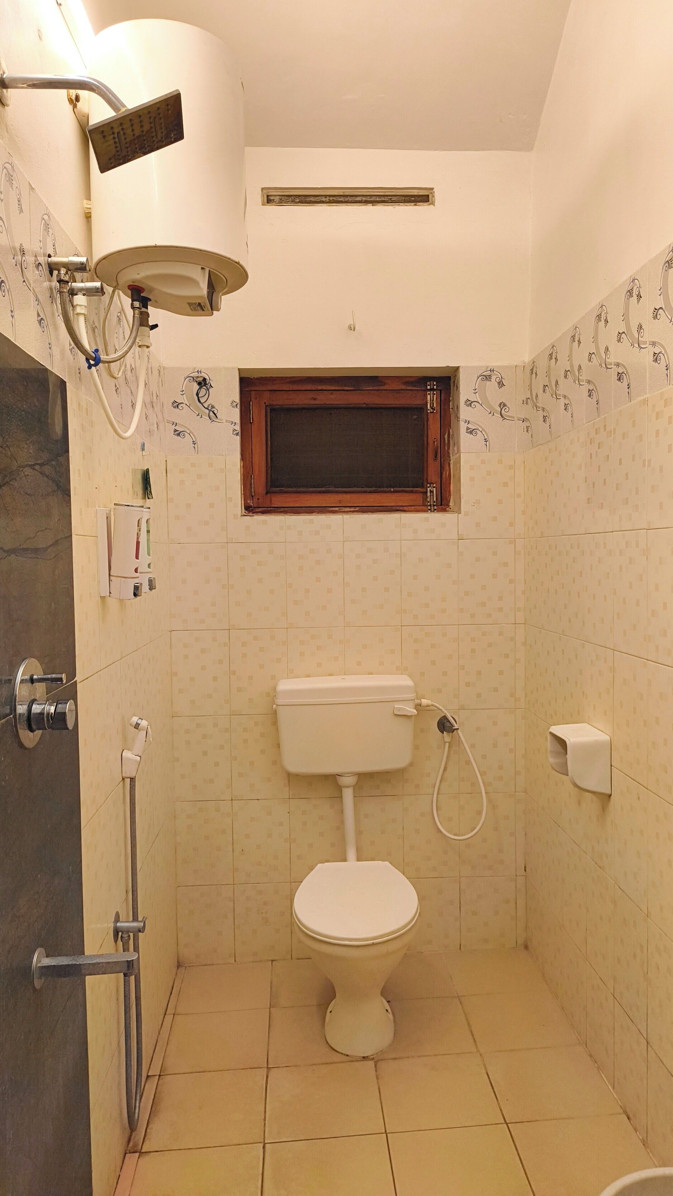 Een kleine badkamer met toilet, douche en raam.