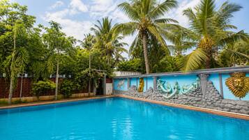 A swimming pool with a decorative wall featuring a mermaid, a golden statue, and a lion head.