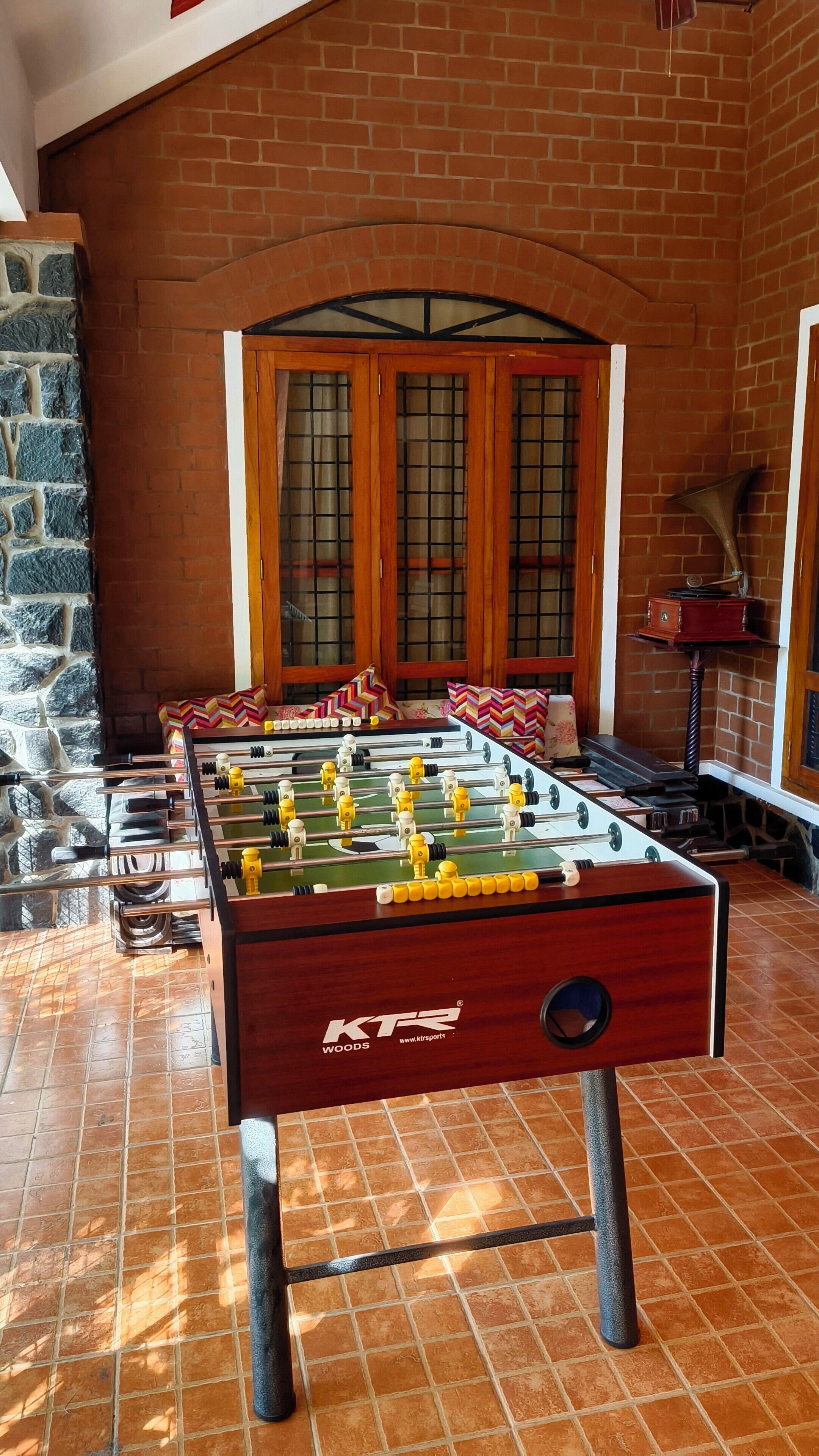 Una mesa de fútbol en una habitación con paredes de ladrillo y un muro decorativo de piedra.