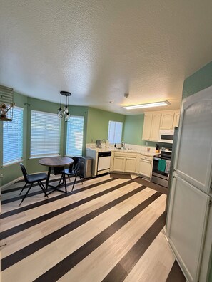A kitchen with a striped floor, white cabinets, and a dining area with a table and chairs. - Spacious Home Near Napa Valley & Six Flags in Suisun City (Suisun City)