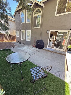 A residential backyard with a patio table, a lawn chair, a barbecue grill, and a wooden fence. - Spacious Home Near Napa Valley & Six Flags in Suisun City (Suisun City)
