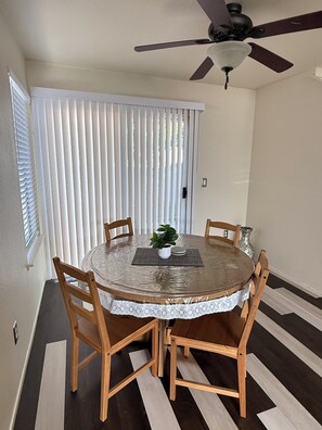 A dining area with a round table, four chairs, a ceiling fan, and a window with blinds. - Spacious Home Near Napa Valley & Six Flags in Suisun City (Suisun City)