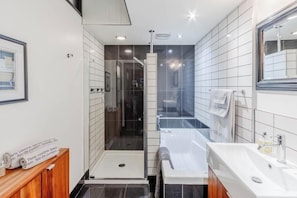A modern bathroom with a glass-enclosed shower, a separate bathtub, and a vanity with a mirror. - Appartement du Vieux-Québec (Québec)