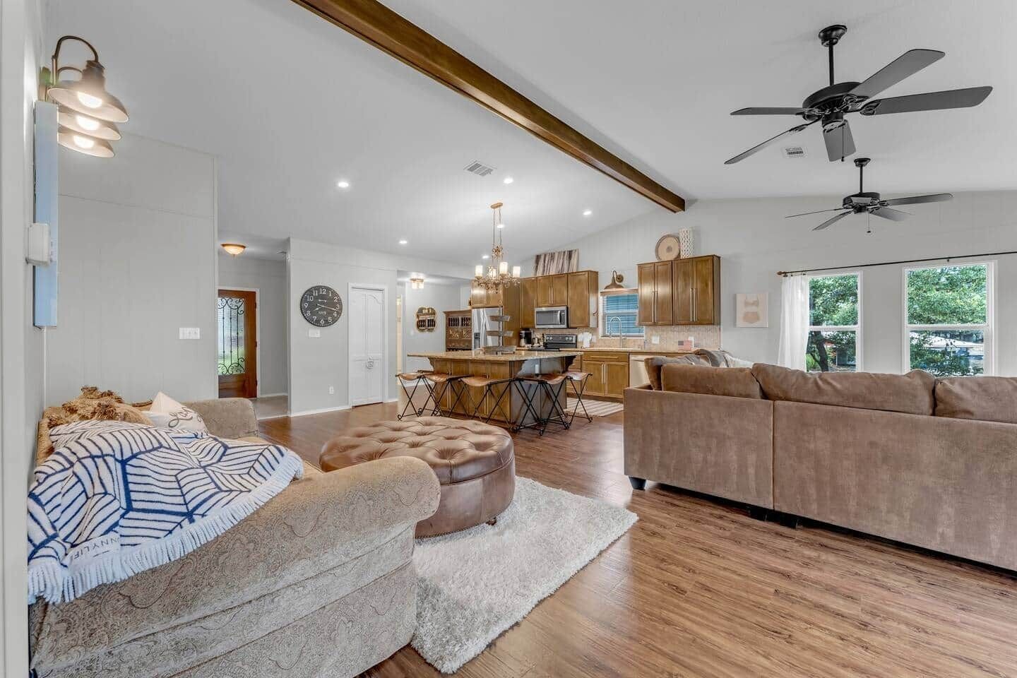A spacious living area with a sofa, ottoman, and a dining area with a bar.