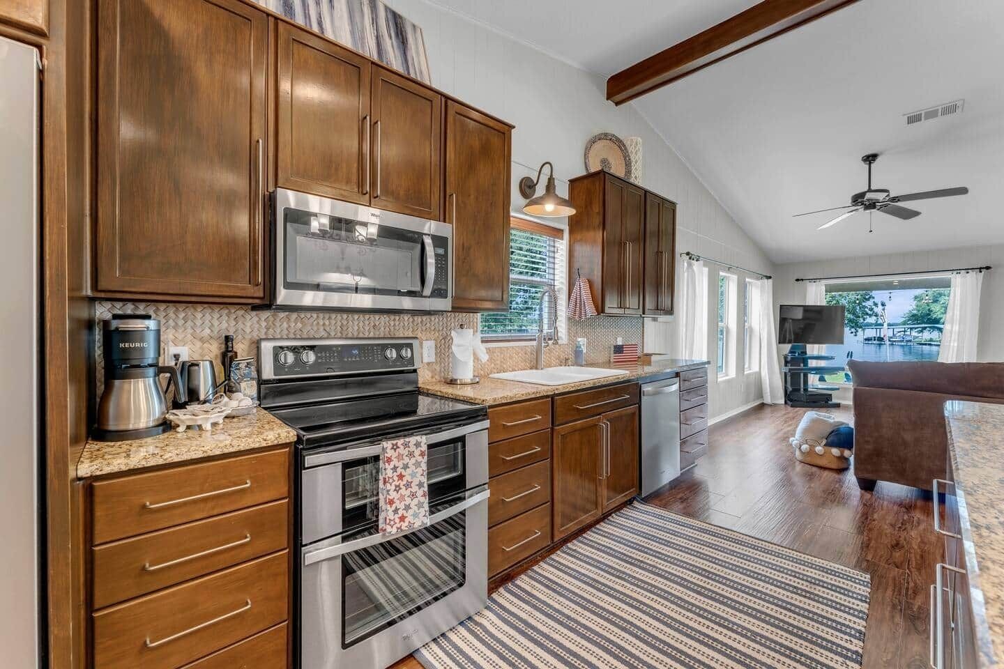 A kitchen with wooden cabinets, stainless steel appliances, and a large window.