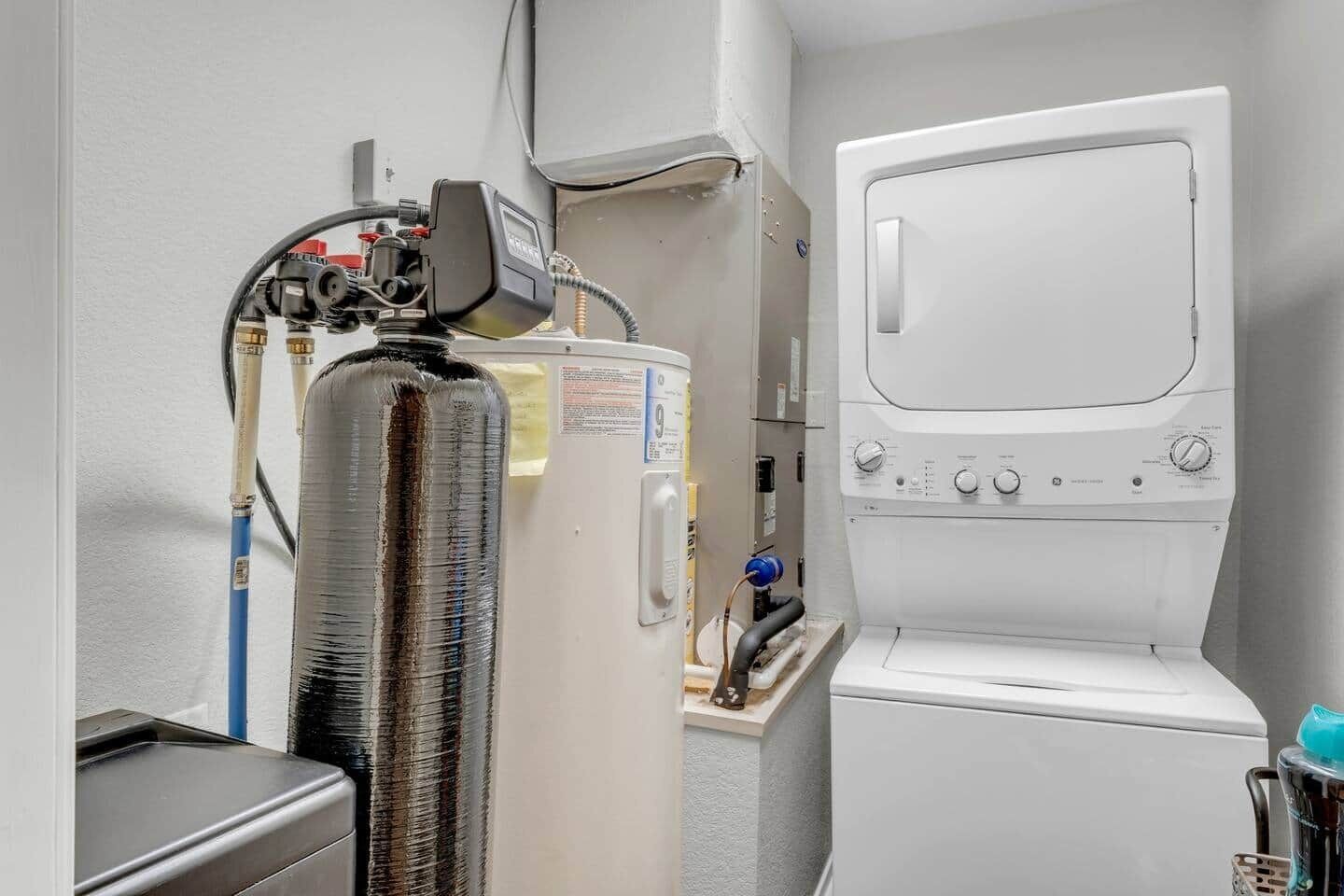 Ein kleines Zimmer mit Durchlauferhitzer, Waschmaschine und kleinem Waschbecken.