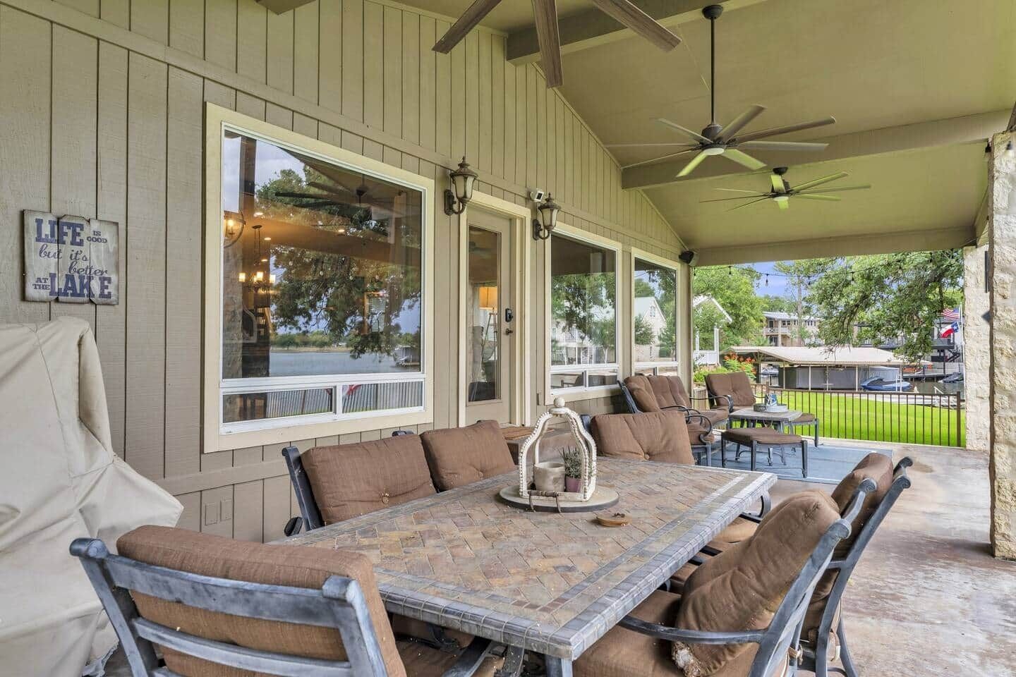 An outdoor covered patio with a dining table, chairs, and a ceiling fan.