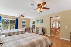 A bedroom with two beds, a ceiling fan, a TV, and a balcony with a view. - Waterfront Escape: Long Mountain Drive Lakehouse! (Llano County)