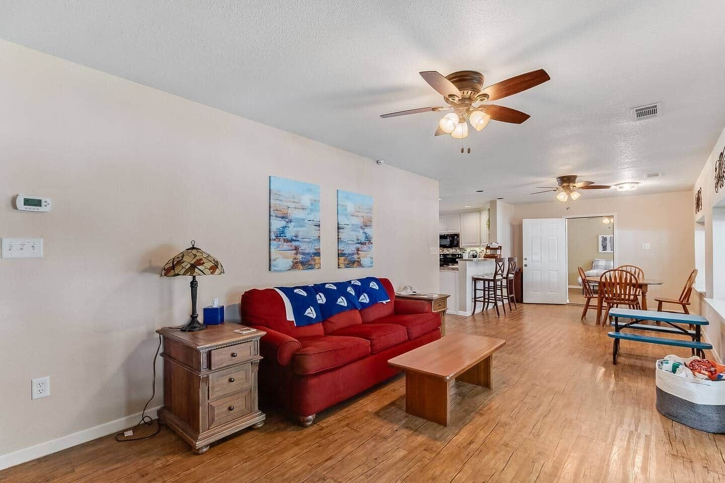 A living room with a red sofa, wooden coffee table, and a ceiling fan.