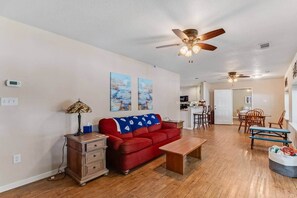 A living room with a red sofa, wooden coffee table, and a ceiling fan.