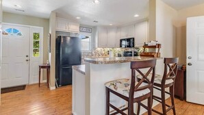 Una cocina con una isla central, un refrigerador y un microondas.