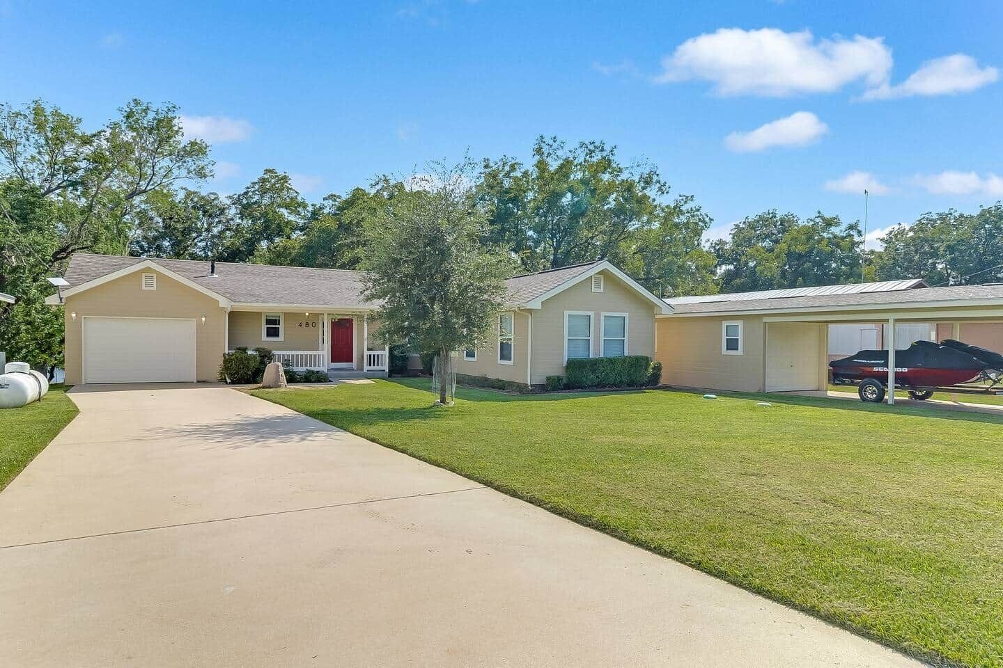 A residential area with two single-story houses, a driveway, and a lawn.