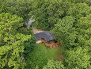 A house surrounded by dense forest with a covered outdoor deck and a visible pathway leading to the entrance. - Treetop Retreat - MTB Oasis-0.8mi to Tunnel Vision (Bella Vista)