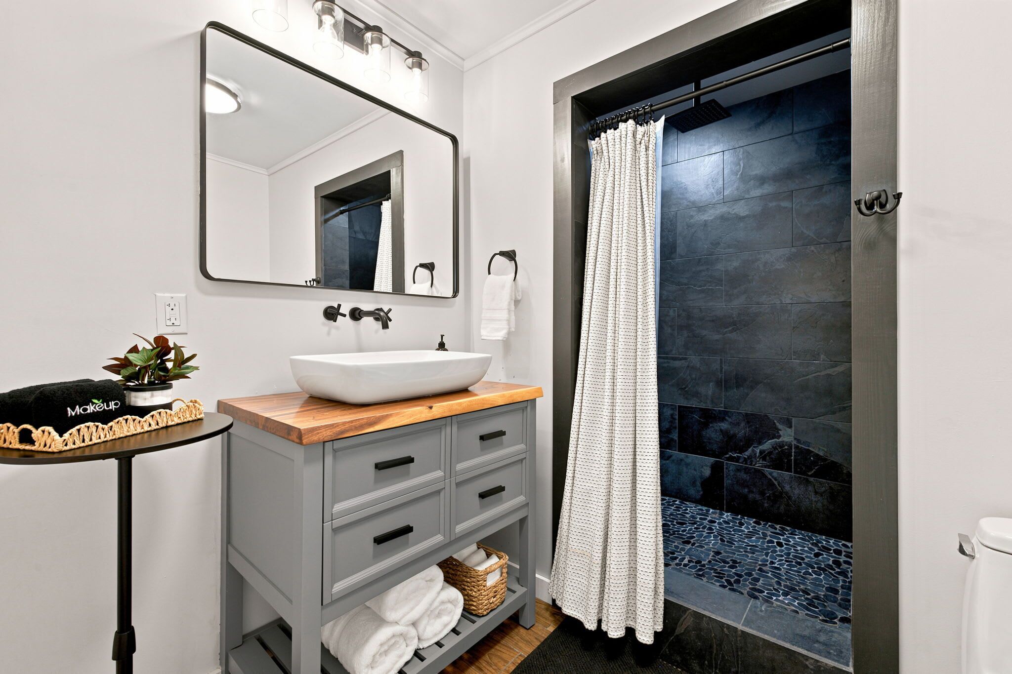 Un baño moderno con lavamanos sobre encimera, espejo, toallero y zona de ducha.