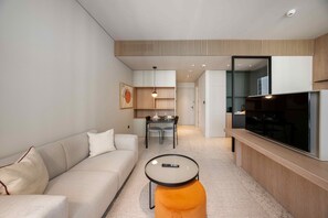 Ein modernes Wohnzimmer mit einer Couch, einem kleinen runden Tisch und einem Fernseher.