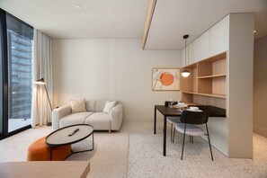 Ein modernes Wohnzimmer mit einer Couch, einem Esstisch mit Stühlen, einem Couchtisch und einem großen Fenster mit Vorhängen.