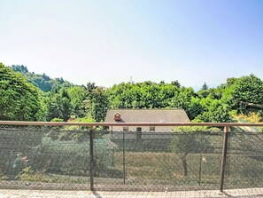 Ein Gebäude mit einem Ziegeldach, umgeben von dichtem Grün und Hügeln im Hintergrund.