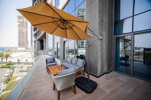 Ein Balkon mit Tisch, Stühlen und einem Koffer, mit Blick auf die Stadt.