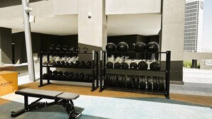 Ein Fitnessstudio mit Gewichten, darunter Kettlebells, Kurzhanteln und Langhanteln.