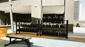 Ein Fitnessstudio mit Gewichten, darunter Kettlebells, Kurzhanteln und Langhanteln.